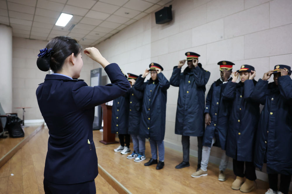 1月18日，外国志愿者在兰州西站客运员（前左）的指导下穿上铁路制服准备上岗。新华社记者　陈斌　摄