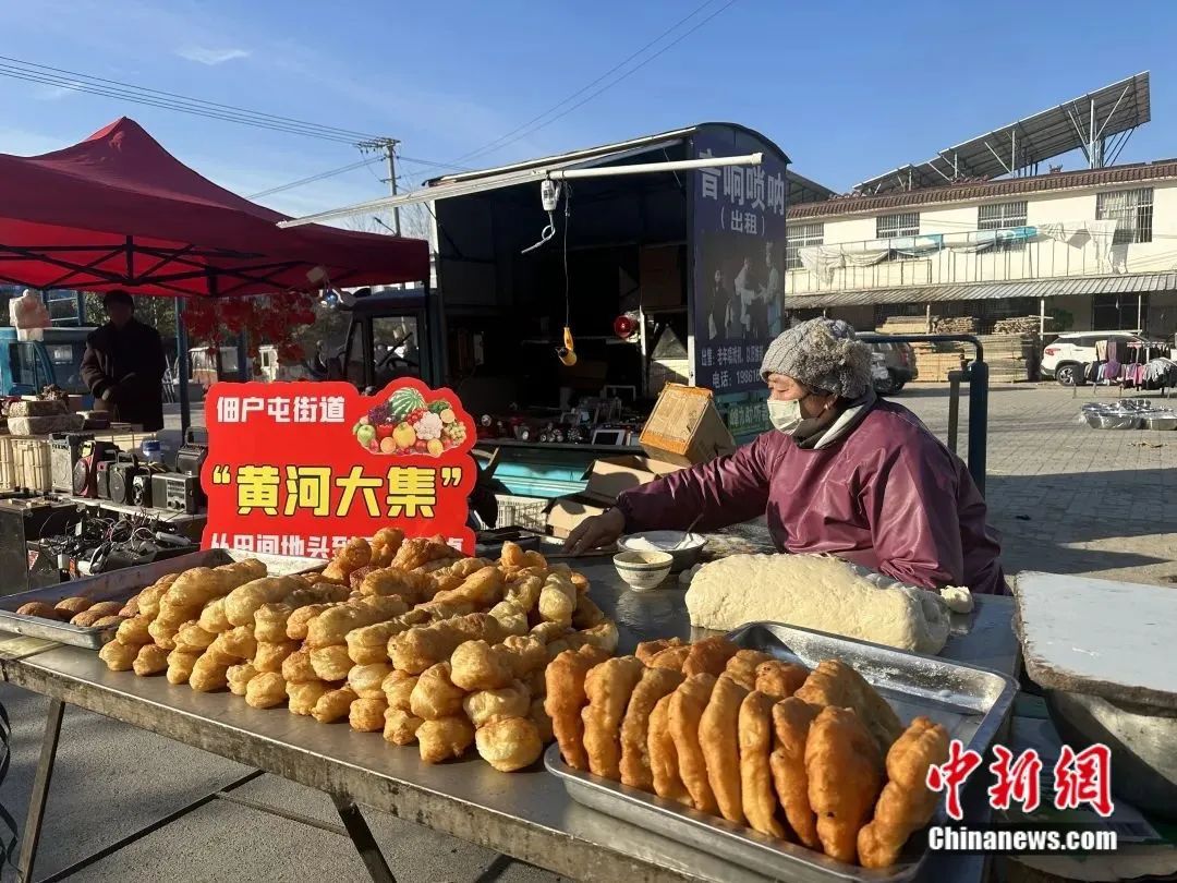 在鲁西新区佃户屯街道“黄河大集”，摊主正在售卖刚出锅的炸油条、炸肉盒。菏泽鲁西新区办公室供图