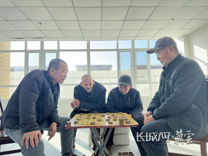 老人们围坐在一起下象棋。通讯员 陈英华 摄