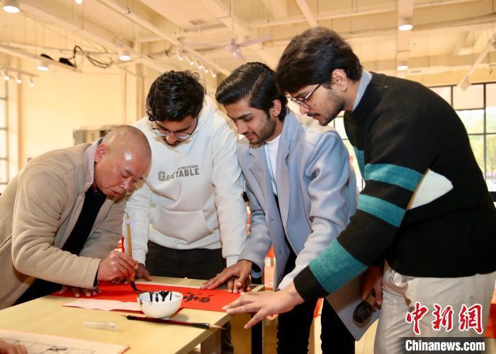 图为外国友人向书法爱好者学习写春联。陈启道 摄