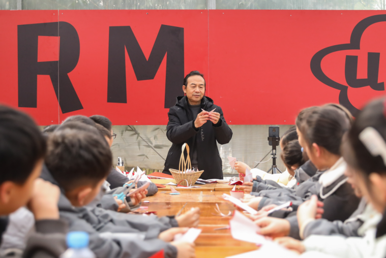 宜春市美术协会老师任静正在介绍剪纸文化来源，手把手教孩子们剪“福”字迎接新年。（袁州区委宣传部供图）