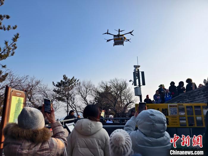 蛇年春节期间，近百名游客在北京八达岭长城南五楼露台附近围观无人机配送外卖。中新社记者 李梦 摄