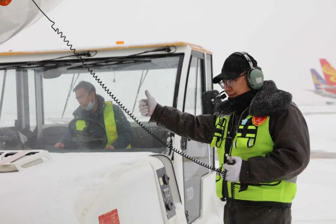 兰州机场机务放行人员通过手势与航空器牵引车驾驶员互相确认位置　张斌　摄