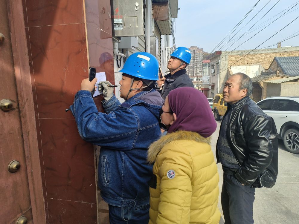 米祥仁供电所工作人员张伟(左一)和刘平(左二)为来电群众解决问题 新华社记者 王紫轩 摄