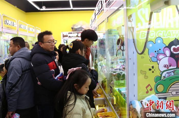 2月1日农历正月初四，河北省邯郸市邯郸道历史文化街区内，游客正在玩“抓娃娃”游戏。中新社记者 韩冰 摄