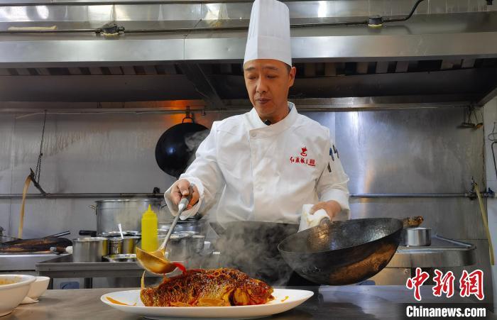 1月22日，罗林完成罾蹦鲤鱼的最后一个步骤，以“热汁儿”浇“热鱼”。杨子炀 摄