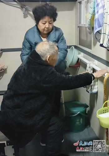 居家适老化改造后，张春森老人可利用厕所内新安装的加长扶手起身。