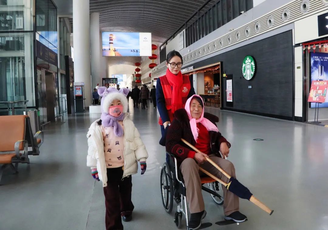 兰州机场“小红帮您”工作人员正在帮助特殊旅客前往登机口　张博　摄