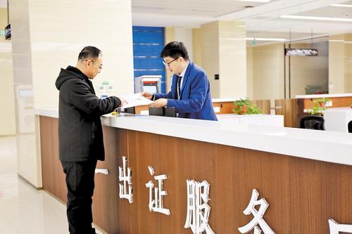 2月5日，在保定市民服务中心，大参林集团河北益友医药连锁有限公司外务经理郑利刚（左）领到了新开门店的《药品经营许可证》。陈 曼摄