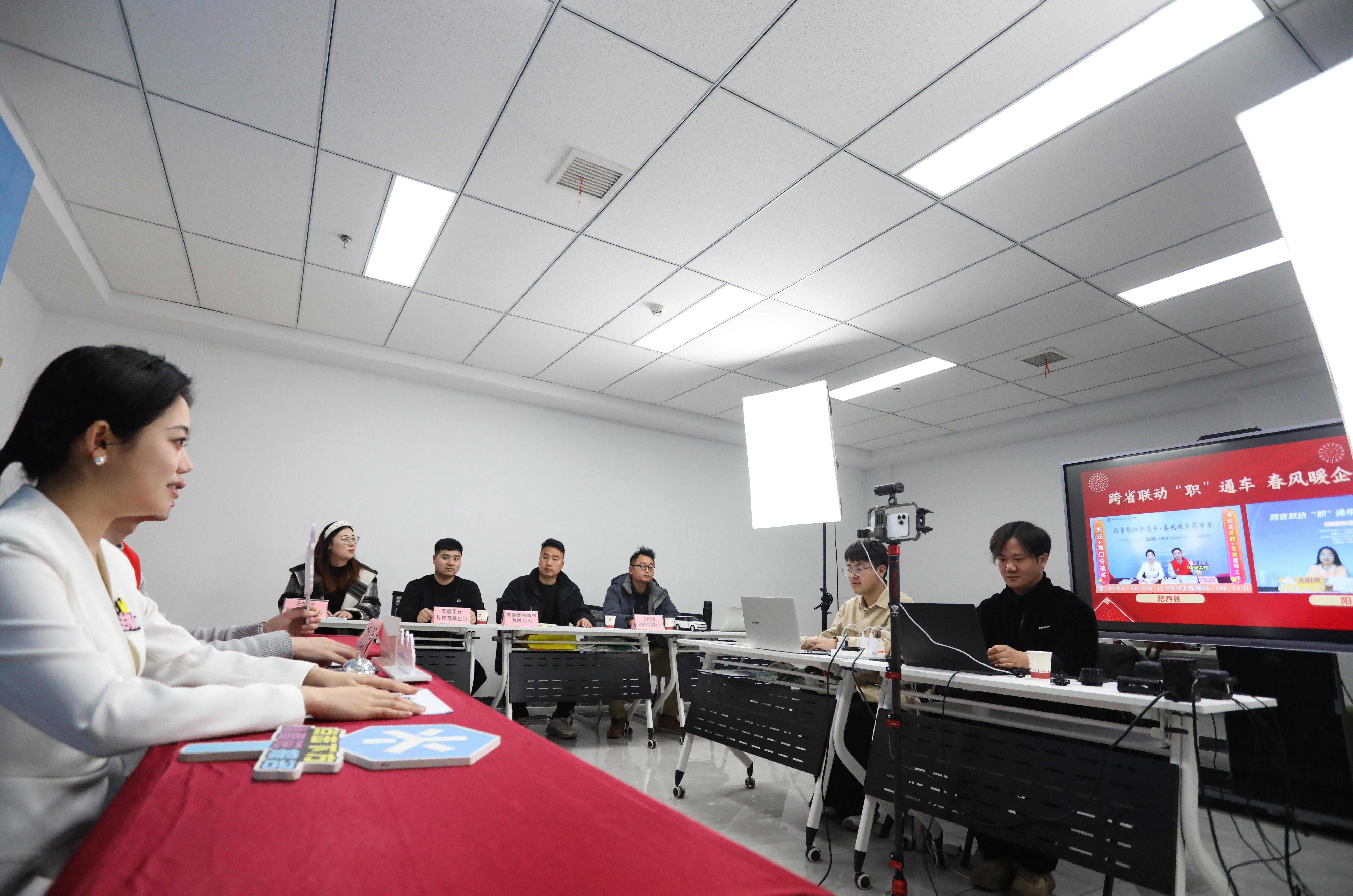(图为:2025年2月14日,在安徽省合肥市肥西县“跨省联动职通车·春风暖企惠万家”直播带岗活动现场,主播和志愿者向异地求职者介绍岗位情况。)
