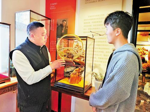 2月7日,在石家庄许红阳木雕博物馆,馆长许红阳(左)正在给游客讲解木雕文创产品。 本报记者 赵泽众摄