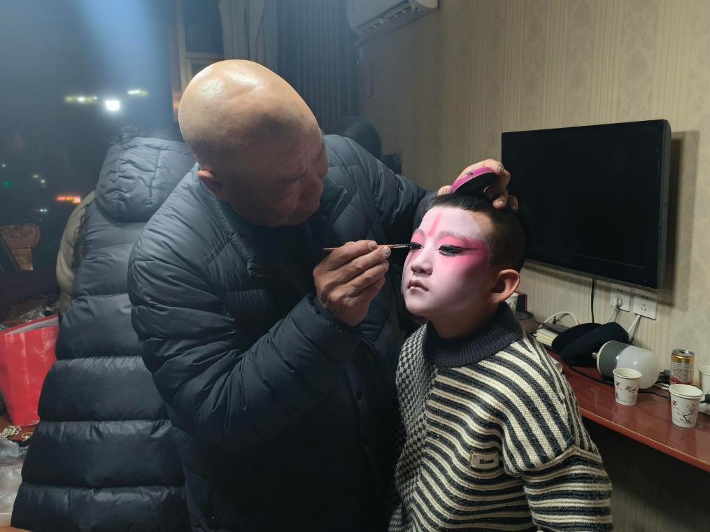 朱富同（左一）在为高抬小演员上妆　新华社记者　王紫轩　摄