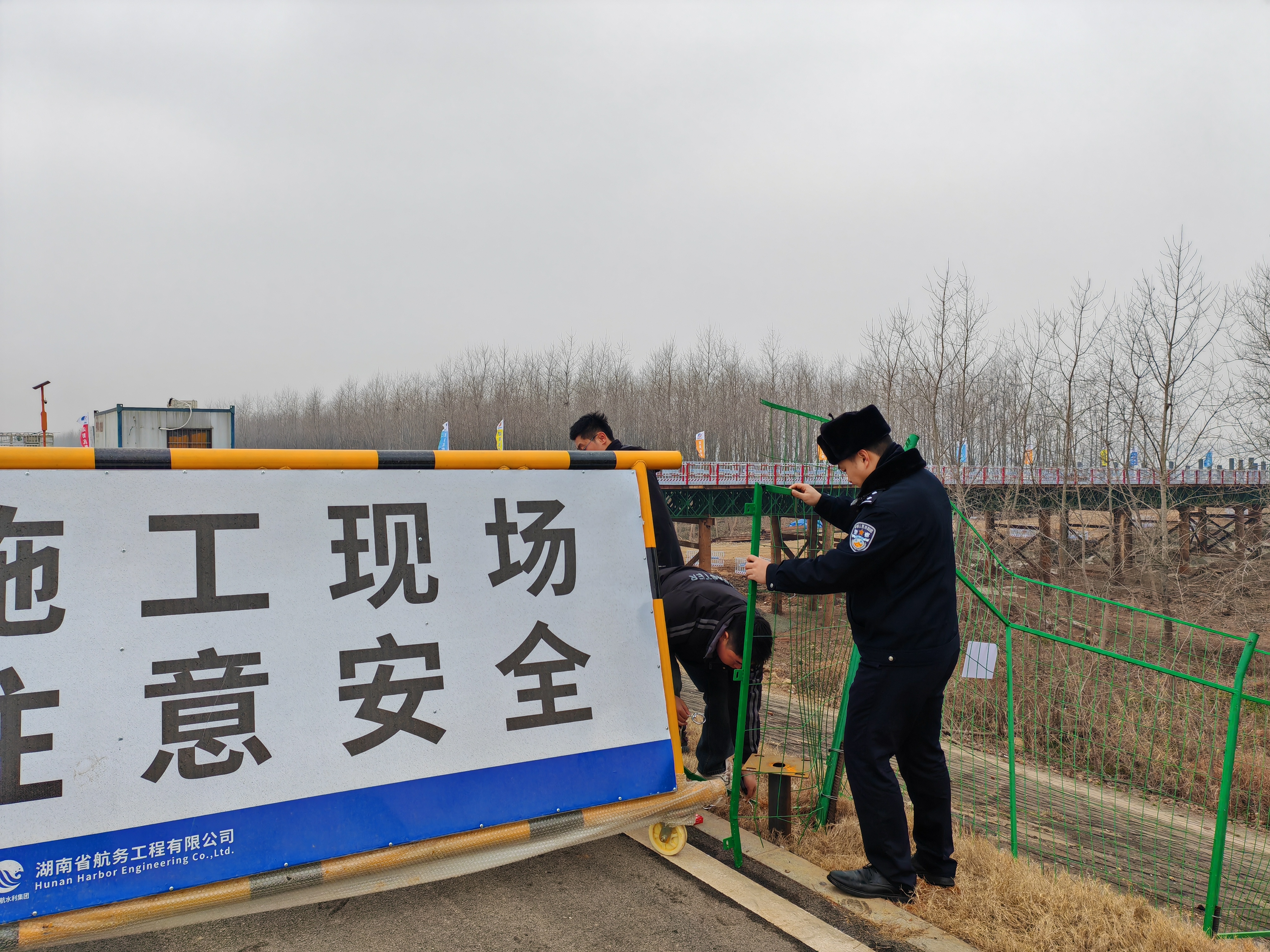 民警协助工地员工修补围栏