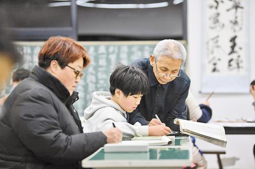 2月11日晚，邯郸市“书法爷爷”李贵江在简易课堂内，手把手教授学生练习书法。董 源摄