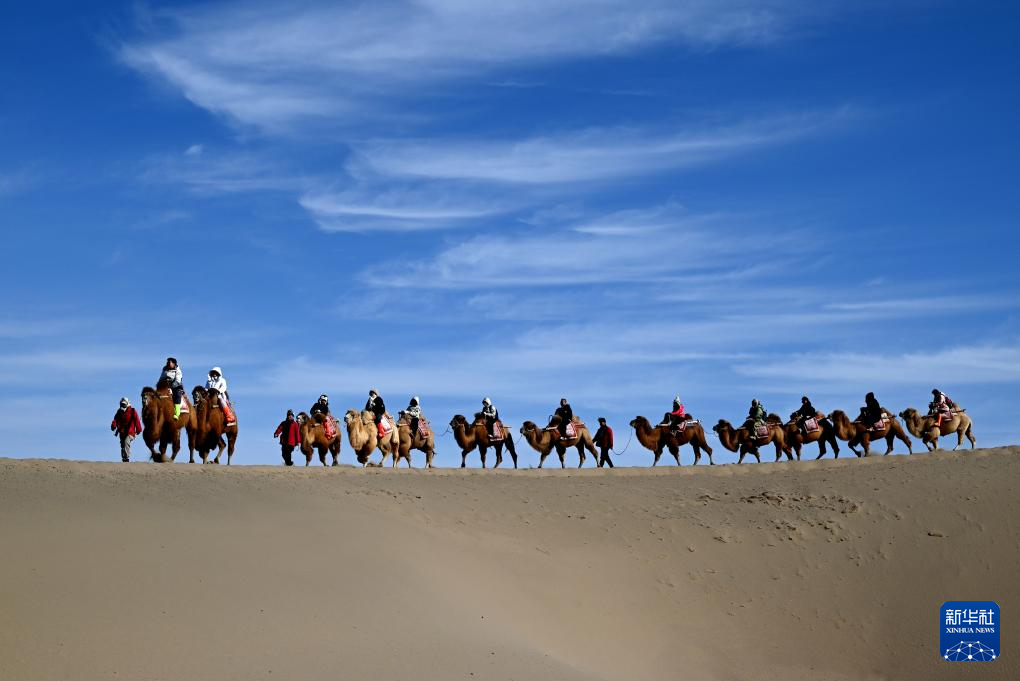 2025年2月4日,游客在敦煌鸣沙山月牙泉景区骑骆驼游览。新华社发(张晓亮 摄)
