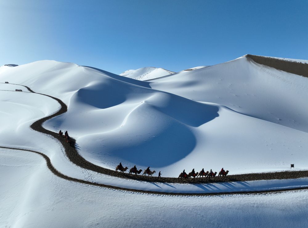 2023年11月15日,游客在甘肃省敦煌市鸣沙山月牙泉景区欣赏雪景。(无人机照片)张晓亮 摄