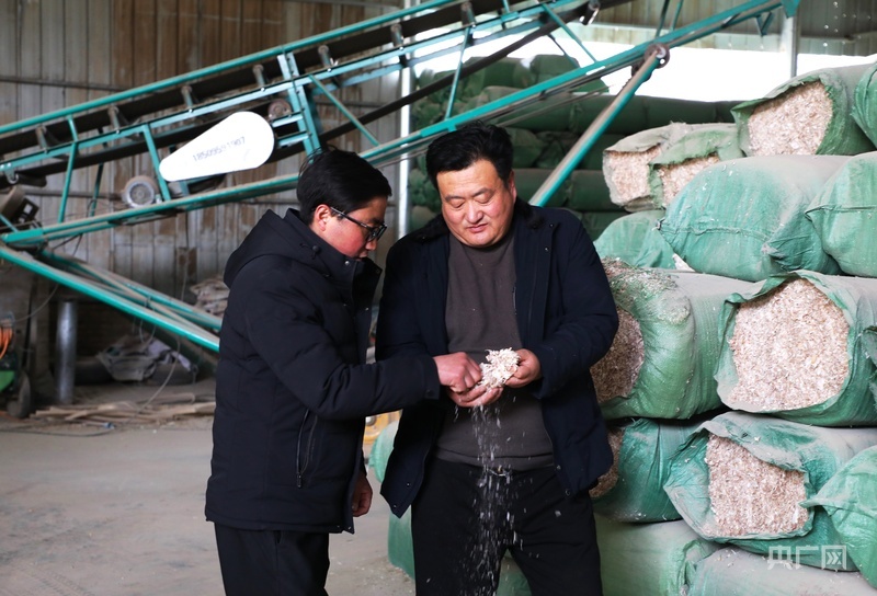 张鹏飞（右）查看饲草料配比情况（央广网发　郭海霞　摄）