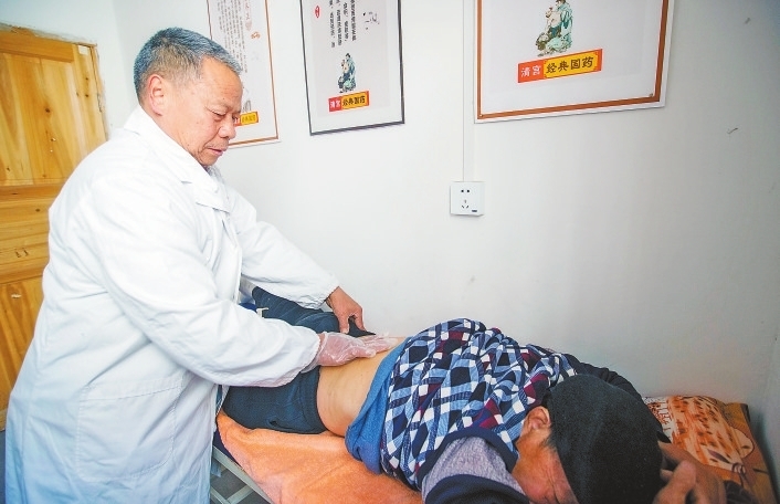 邬德祖给腰椎间盘突出的村民按摩治疗。