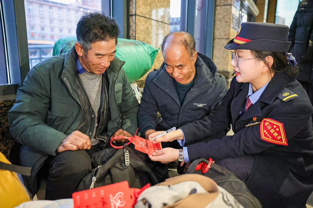 鹰潭站工作人员为旅客行李戴好爱心行李牌。（张坤茹 摄）