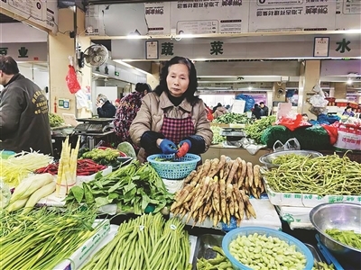 在叠山路农贸市场，蔬菜摊位上摆满了各种春菜