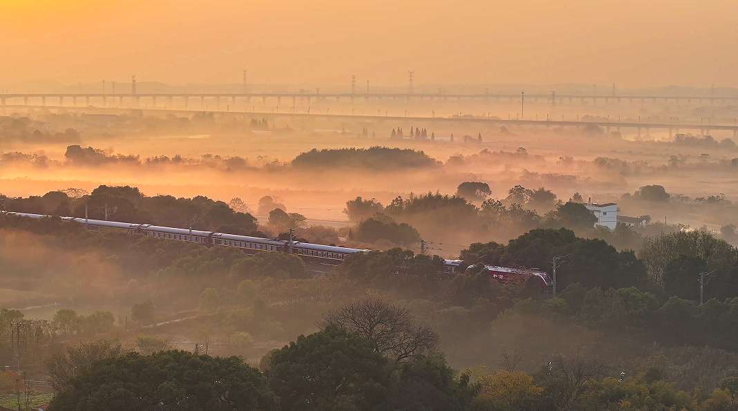 清晨，一辆旅客列车在京九线向塘区段迎着金色的朝阳向终点站驶去。（陈平 摄）