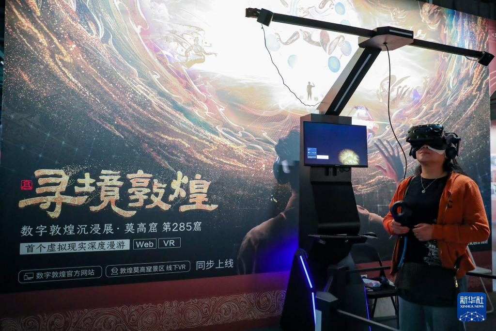 2024年9月22日,在敦煌研究院“典范”“高地”建设成果展上,游客借助VR设备沉浸式游览莫高窟第285窟虚拟场景。新华社记者 郎兵兵 摄