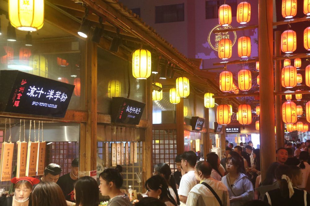 2024年8月17日,游客在甘肃省敦煌夜市沙州食驿品尝地方名优小吃。张晓亮 摄