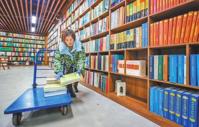 工作人员将新搜集到的书籍分类后放入书架。