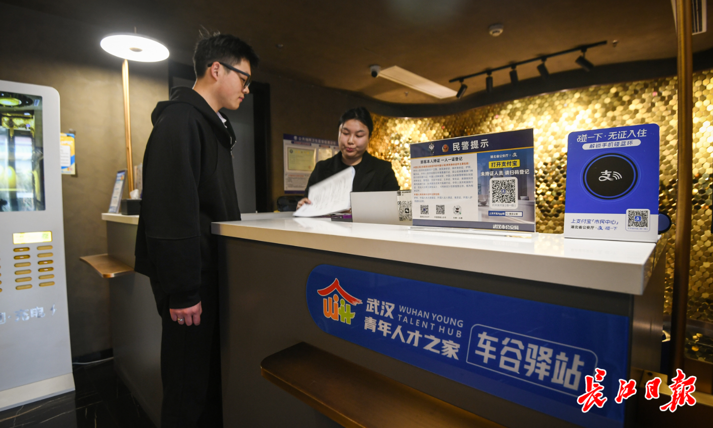 来自湖北十堰的储鑫在酒店前台办理入住手续。 记者史伟 摄