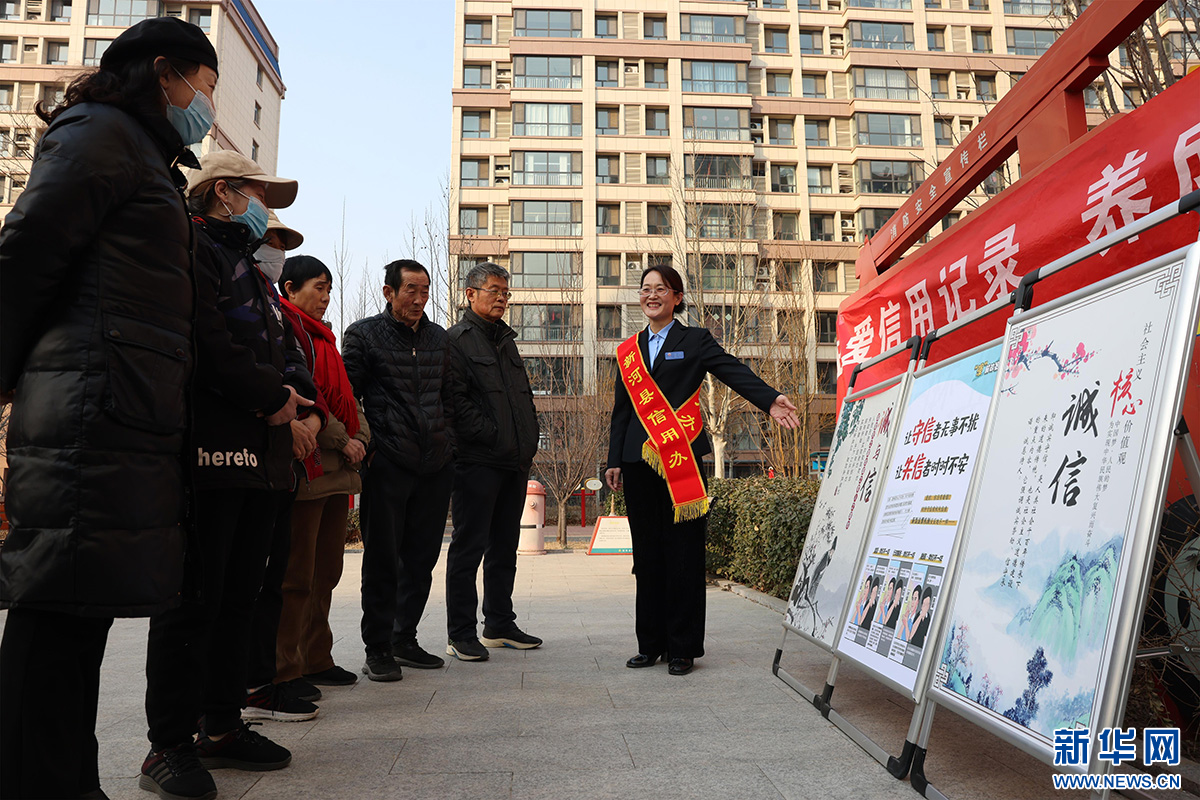 新河县行政审批局工作人员为社区居民讲解信用知识。新华网发 李世强 摄