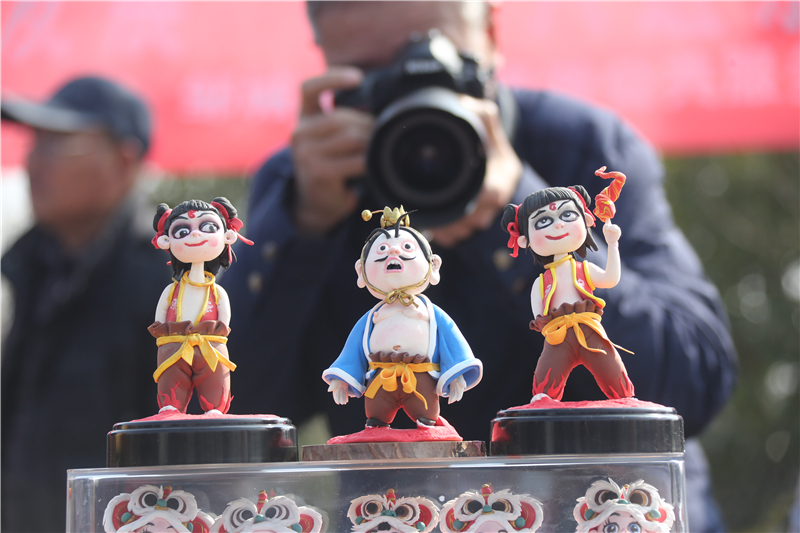 2月28日，在山东邹城峄山庙会上，游人拍摄面塑工艺品。