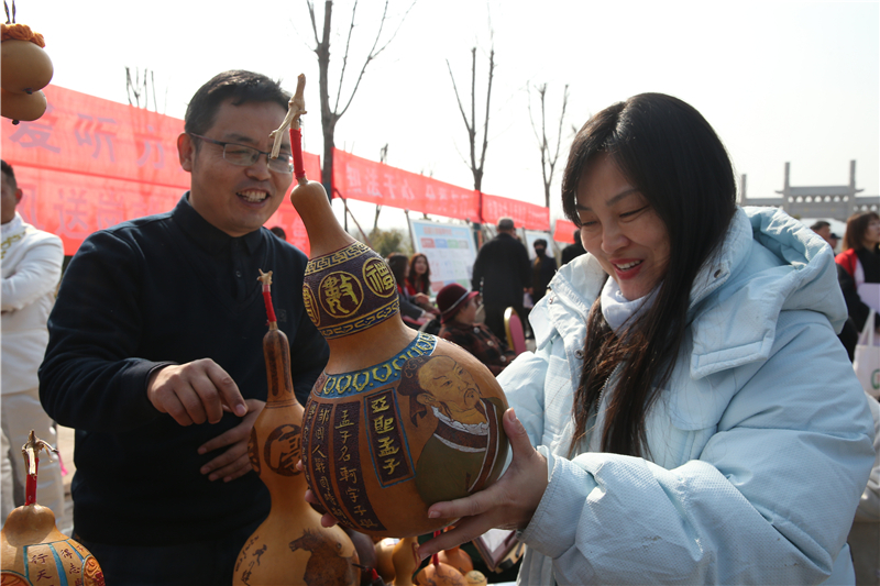 2月28日，在山东邹城峄山庙会上，非遗传承人向游人介绍雕刻葫芦工艺品。