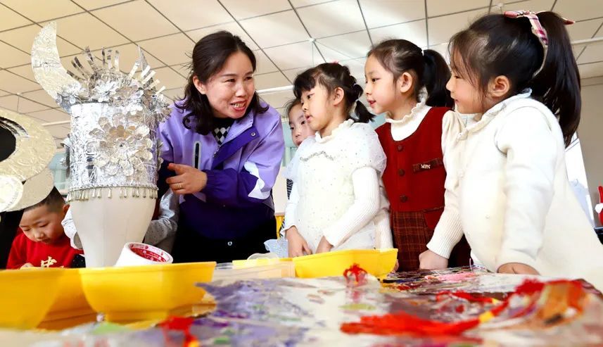 张掖市临泽县第二幼儿园老师给幼儿介绍苗族头饰制作方法