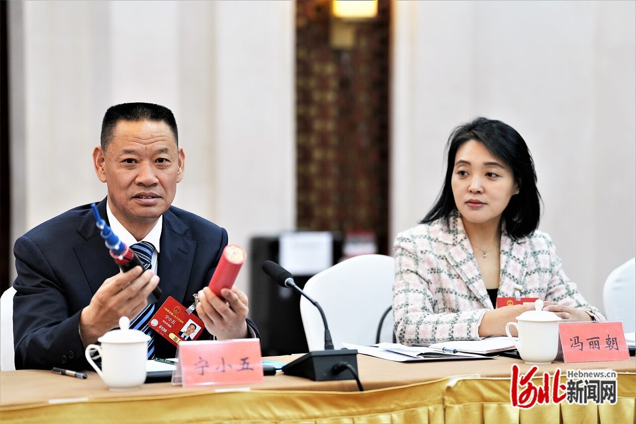 3月7日上午，河北省代表团小组会议上，宁小五代表（左）展示当地共享车间生产的电缆。 河北日报记者 许佳奇摄.JPG