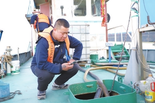 污染物接收员陈正印在用手机拍下接收船收集污水的照片。