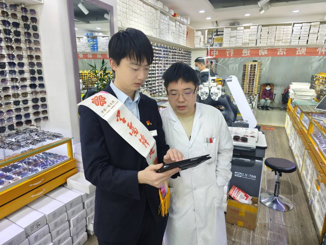 (建设银行哈尔滨住房支行青年志愿者为哈尔滨道里区财喜眼镜商店办理相关业务)