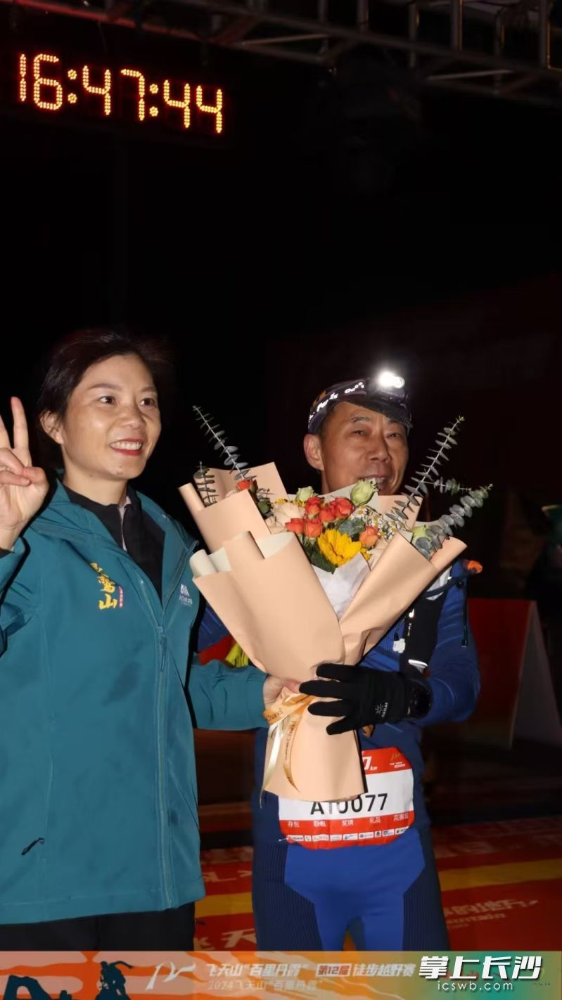 飞天山徒步越野赛后，白丽琴为师父湛稼勤献花。