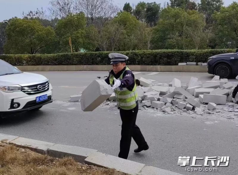 民警化身“搬砖工”，清理路面障碍物。长沙晚报通讯员 凌菱 供图