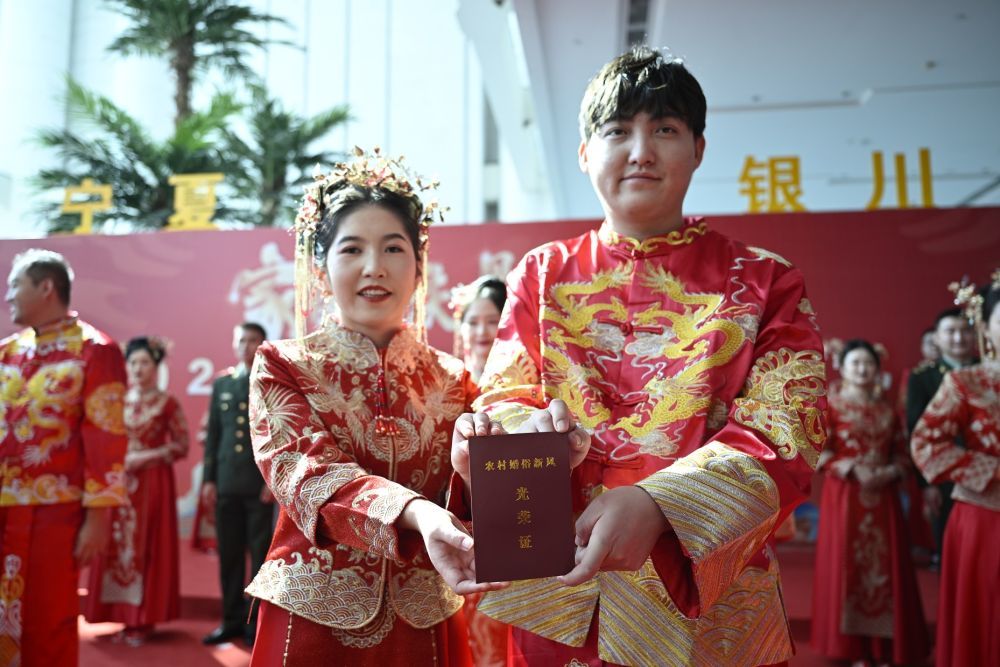 2024年9月22日,在宁夏银川市,新人在“家国同庆 见证幸福”2024年全国万人集体婚礼宁夏分会场展示“农村婚俗新风光荣证”。新华社记者 王鹏 摄