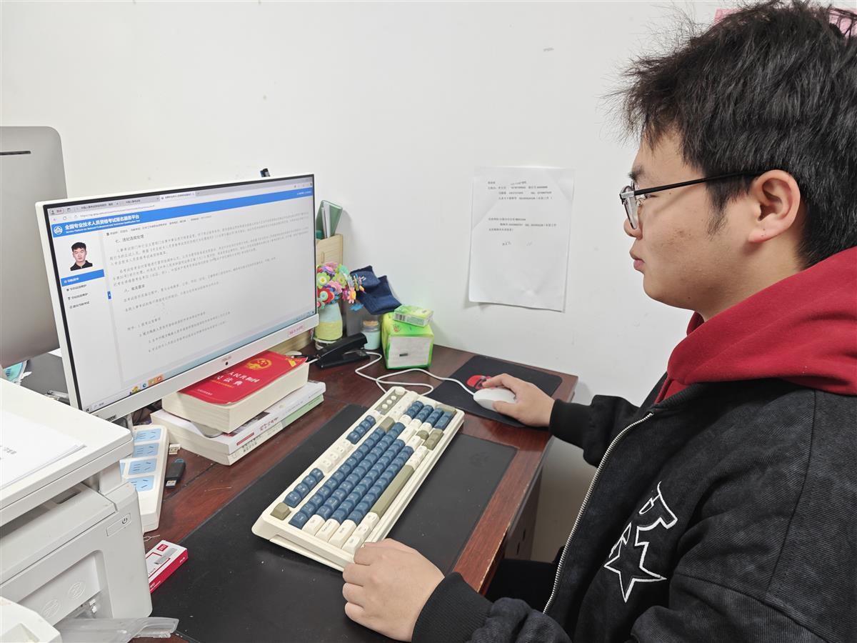 郑继伟正在电脑上进行社会工作者职业资格考试报名