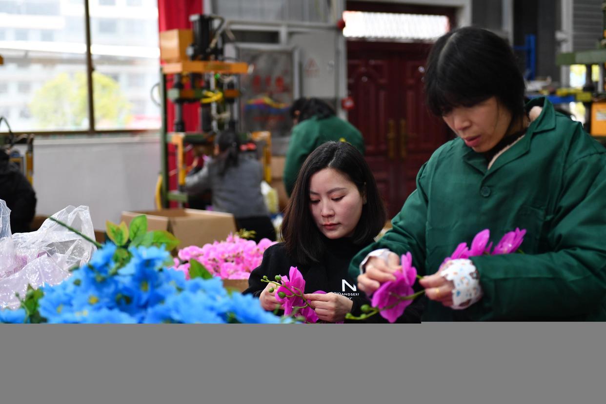 3月5日,在湖南省邵阳市城步苗族自治县,杨淑亭(左)在生产车间指导工人制作仿真花。