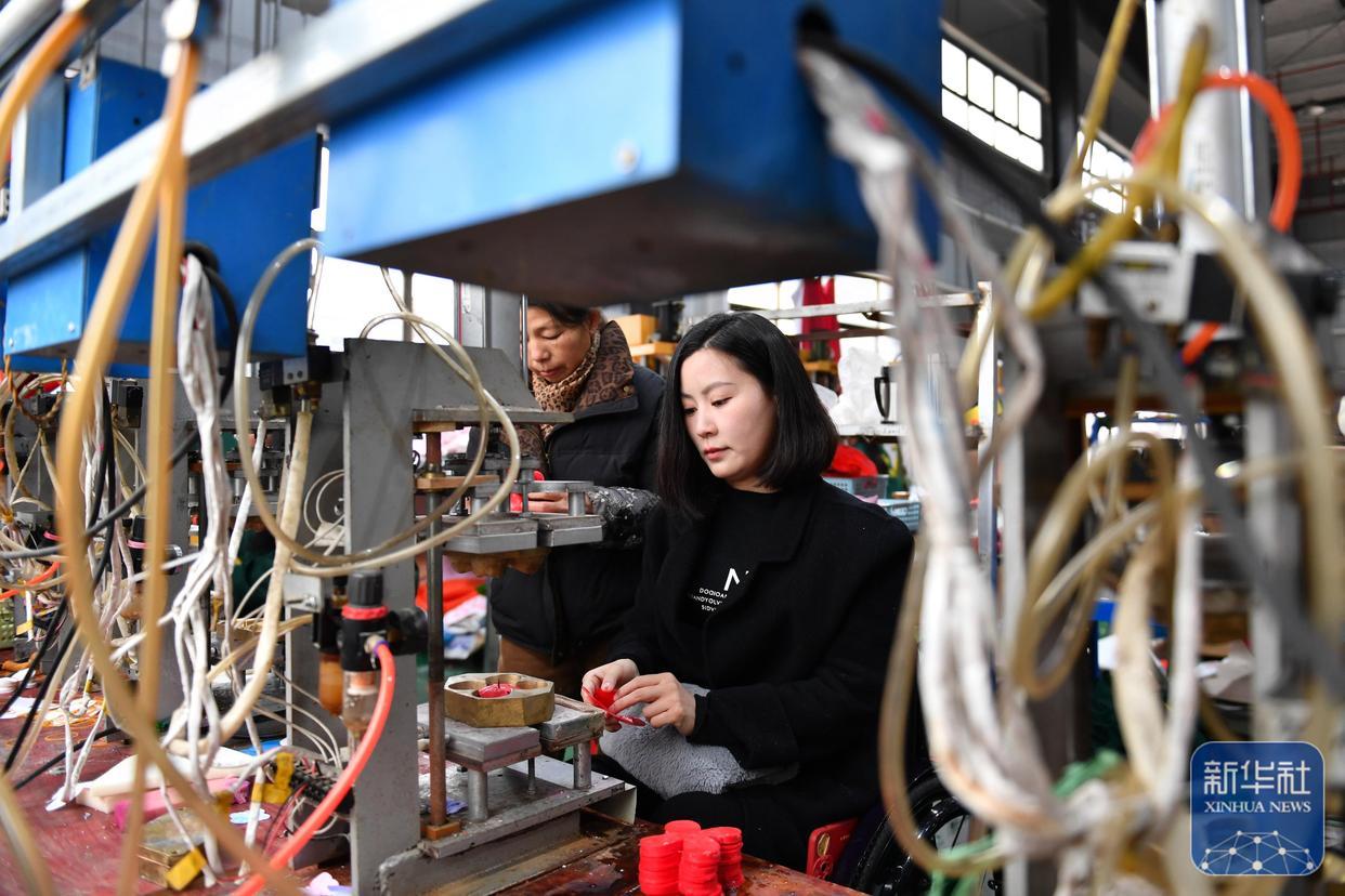 3月5日,在湖南省邵阳市城步苗族自治县,杨淑亭(右)在生产车间指导工人制作仿真花。
