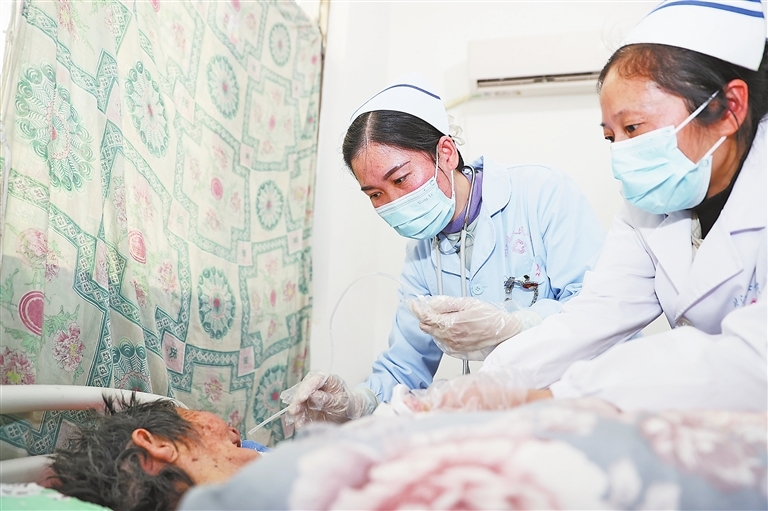 3月11日,在峡江县水边镇佩贝村,“网约护士”严立平(右)和温文娟为患者更换留置胃管。