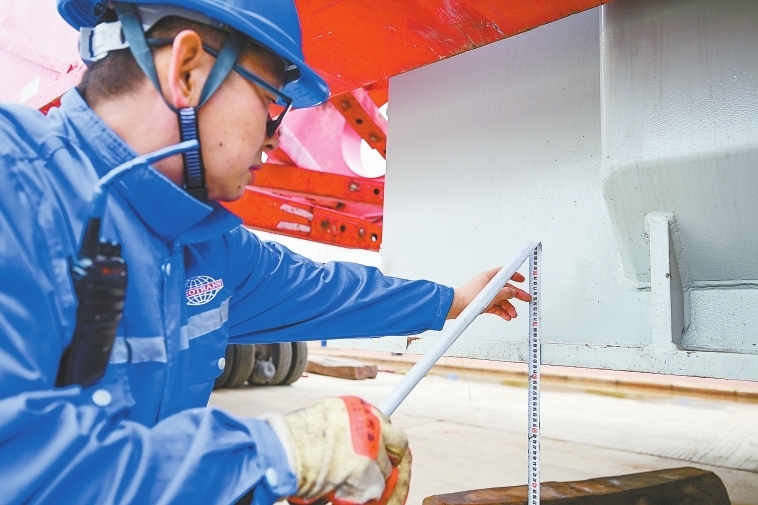 工作人员利用尺子测量变压器离地高度。