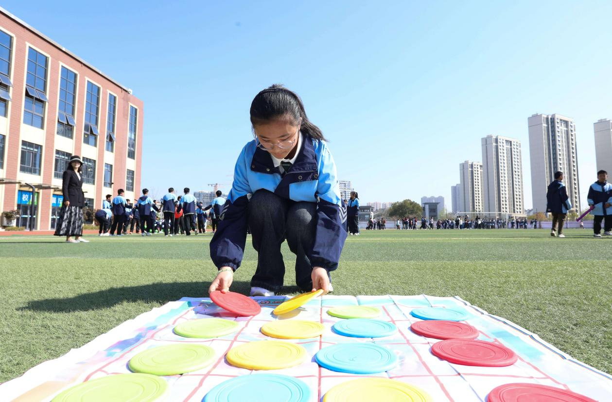 (图为:2025年3月25日,一名学生在安徽省合肥市肥西县上派镇安徽师范大学附属肥西第二中学操场上开展“彩色移盘”心理团辅游戏。)