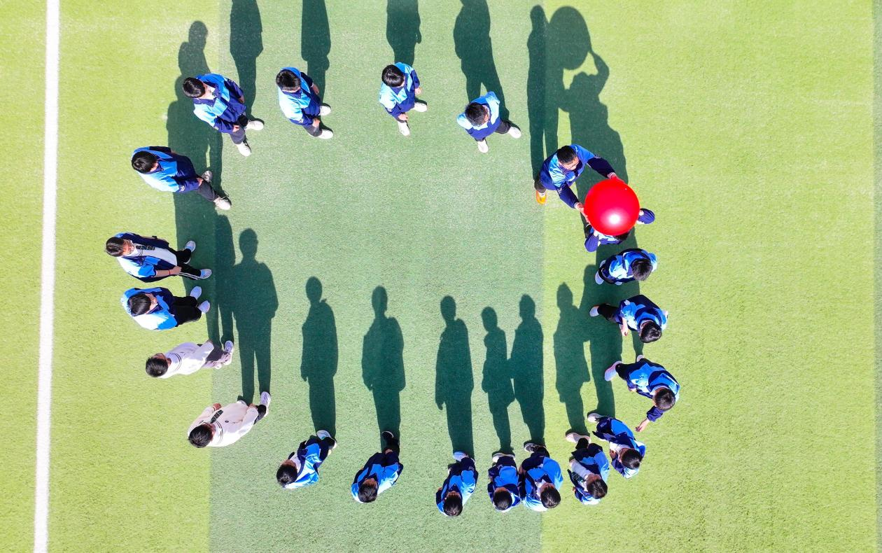 (图为:2025年3月25日,在安徽省合肥市肥西县上派镇安徽师范大学附属肥西第二中学校园内,学生们利用阳光大课间时间在操场上开展“能量传输”心理团辅游戏。)