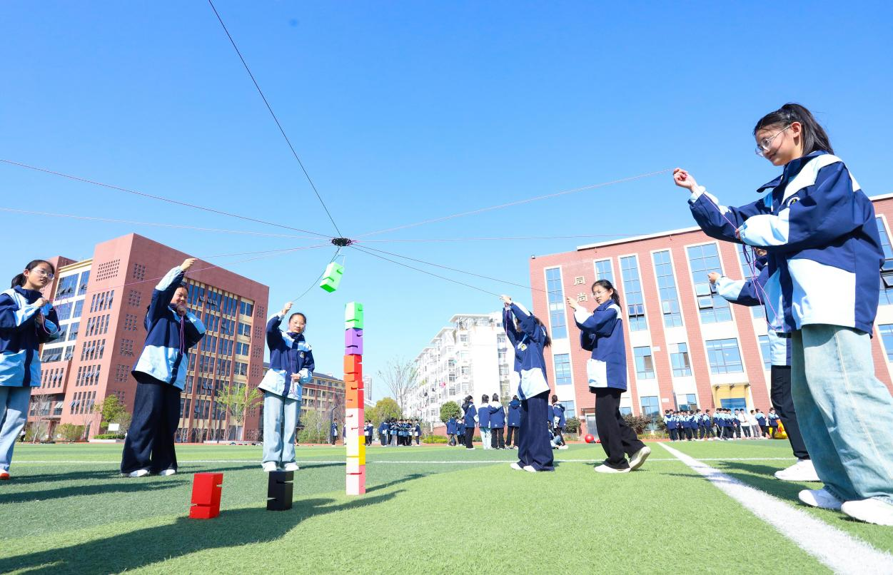 (图为:2025年3月25日,在安徽省合肥市肥西县上派镇安徽师范大学附属肥西第二中学校园内,学生们利用阳光大课间时间在操场上开展“合力筑塔”心理团辅游戏。)