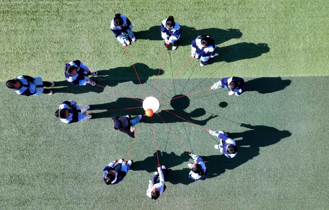 (图为:2025年3月25日,在安徽省合肥市肥西县上派镇安徽师范大学附属肥西第二中学校园内,学生们利用阳光大课间时间在操场上开展“同心击鼓”心理团辅游戏。)