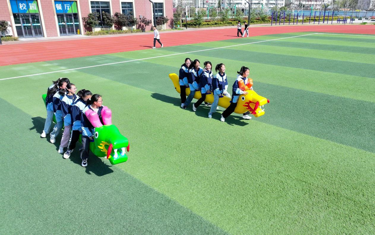(图为:2025年3月25日,在安徽省合肥市肥西县上派镇安徽师范大学附属肥西第二中学校园内,学生们利用阳光大课间时间在操场上进行“旱地龙舟”趣味运动。)