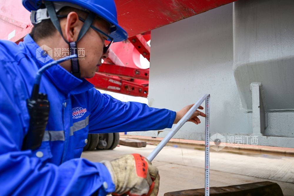 工作人员利用尺子测量变压器离地高度。